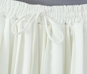 Detailed close-up of white pleated skirt waistband with elastic band and drawstring cord