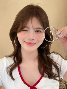 Detailed view of silver hoop earrings in three sizes shown worn and held by a model