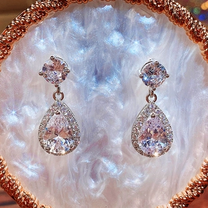 Macro detail of teardrop halo earrings with AAA zircon stones on a pearlescent base
