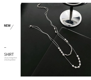 Macro shot of double-layered titanium steel necklace featuring white pearls and beads