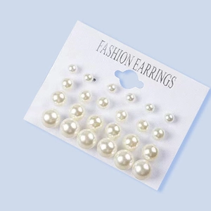 Detail view of 12 pairs of minimalist white pearl earrings in various sizes on a card