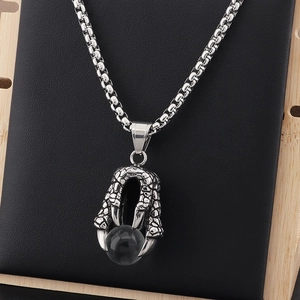 Detailed view of a silver dragon claw pendant holding a black bead on a box chain