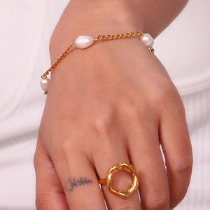 Close-up of golden pearl bracelet and irregular round ring on model wrist