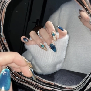 Luxurious blue cat-eye press-on nails with sapphire accents and gold embossed metal details