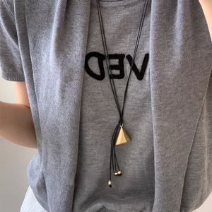 Close-up of golden geometric triangle pendant on adjustable black leather cord necklace