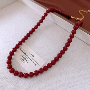 Close-up of vintage deep red round bead necklace with adjustable gold extension chain