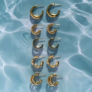 Detailed set of five gold titanium steel earrings displayed on a blue ripple background
