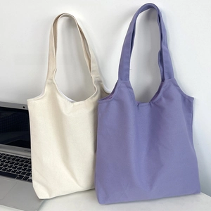 Detail view of solid color canvas tote bags in cream and lilac for custom logo printing