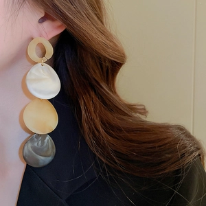Close-up of a model wearing tiered acrylic teardrop tassel earrings in multi-color resin