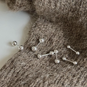 Polished silver sphere studs in various sizes on a brown knit texture backdrop