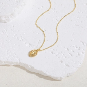 Detailed macro view of gold Virgin Mary pendant necklace with zircon on a marble block
