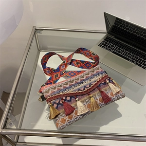 Detailed close-up of ethnic crossbody bag with colorful fringe and woven shoulder strap