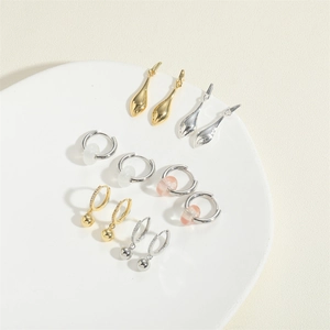 Detailed collection of minimalist drop earrings with beads and crystal charms on a white stand