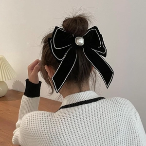 Détail d'un grand nœud à cheveux en velours noir avec perle sur une coiffure élégante