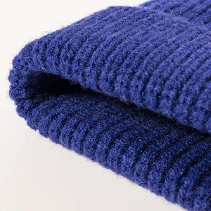 Primo piano di un berretto in maglia a coste blu scuro con calda trama in lana invernale.