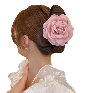 Grande molletta per capelli a forma di rosa in tessuto rosa opaco indossata su uno chignon
