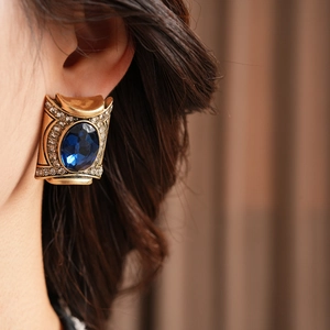 Λεπτομέρεια από vintage χρυσά σκουλαρίκια με μπλε πέτρα και διακοσμητικά στρας