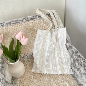 Détail du sac cabas floral en dentelle blanche avec glands et étiquette tissée