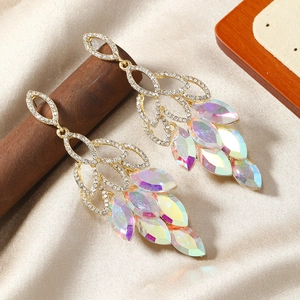 Détail de boucles d'oreilles dorées avec cristaux AB et glands sur fond de satin