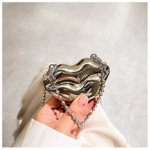 Silver lip-shaped metal mini bag with pearl chain strap held by hand for a stylish look