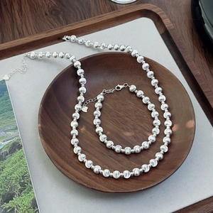 Detailed view of silver cat eye bead necklace and bracelet set in a wooden bowl