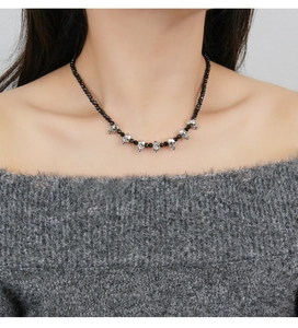 Detail of gothic black beaded necklace with silver skull charms worn by a model