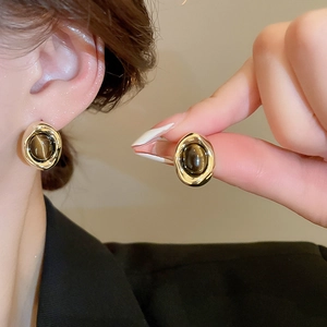 Detailed view of vintage gold plated tiger eye stone earrings on a model’s ear