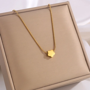 Detailed close-up of a golden flower pendant necklace on a beige velvet jewelry box
