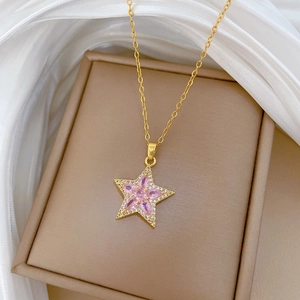 Gros plan du collier doré avec pendentif étoile rose et détails en zircon brillant