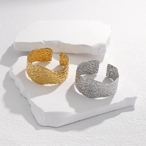 Detailed view of wide gold and silver cuff bracelets with hammered metal textures