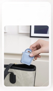 Mini round jewelry travel case in sky blue faux leather being placed into a larger bag