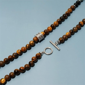 Detail of tiger eye bead necklace featuring a silver T-bar clasp and engraved metal bead