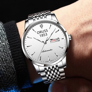 Close-up of silver business watch on wrist with white dial and automatic calendar display