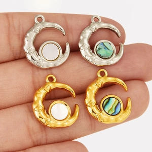 Detail of moon-shaped pendants with white shell and abalone inlay in gold and silver