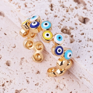 Macro shot of gold-plated evil eye ring with colorful enamel inlay on stone surface