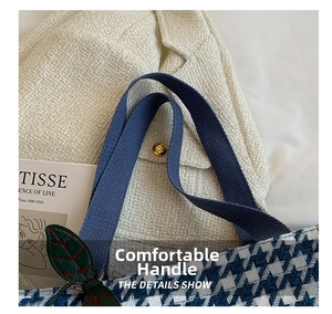 Close-up of blue houndstooth tote bag with thick ribbon handles and leaf charm detail