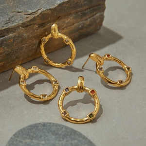 Golden stainless steel hoop earrings with colorful gemstones on natural rock