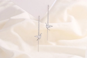 Detailed view of silver origami bird earring with tassels and shimmering zircon stones
