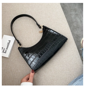 Macro shot of black crocodile pattern faux leather bag with elegant gold hardware detail