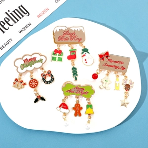 Detail of Christmas metal brooches with hanging snowmen, bells, and holiday text charms