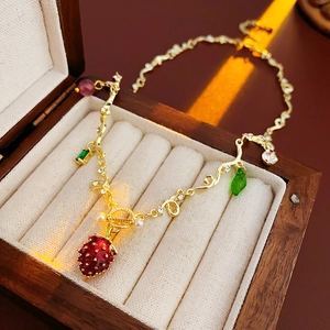 Detailed shot of a red enamel strawberry pendant with gems in a luxury wood jewelry box