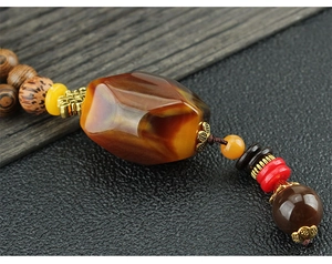 Macro detail of ethnic wooden beads and brown amber pendant on long vintage necklace