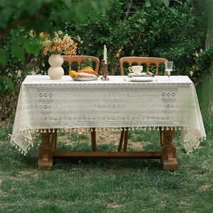 Close-up of beige lace tablecloth with hollow floral patterns and handmade tassels