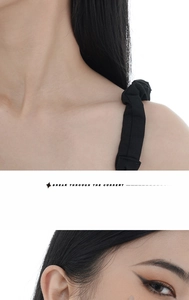 Close-up of black spaghetti straps with pleated fabric detail on a minimalist dress