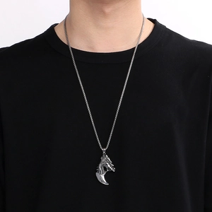 Vue détaillée du pendentif tête de dragon et dent de loup sur chaîne argentée