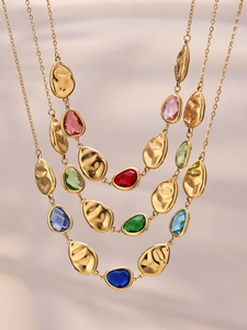 Detailed macro view of multi-layered gold chains with colorful teardrop glass stones