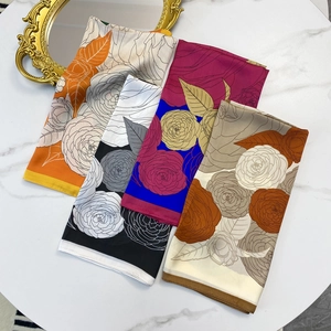 Silk camellia print square scarves in four colors displayed on a white marble background