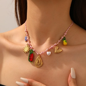 Detail of bohemian woven rope necklace with metal sun, watermelon and heart charms