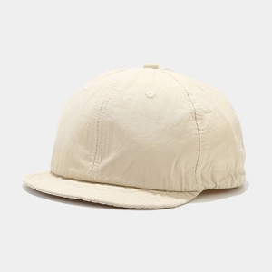 Detail view of beige cotton twill fabric and stitching on a short brim baseball cap