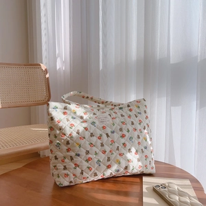 Quilted beige tote bag with vintage bear and floral prints on a wooden surface